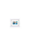 A framed artwork featuring a London docklands scene, with a blue sky and warehouses, float-mounted in a white frame.